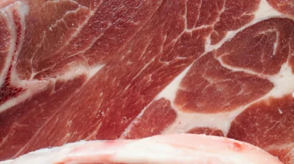Close-up view of raw marbled cuts of red meat with visible fat layers and muscle fibers.