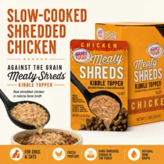 A packet of Shreds Slow Cooked Shredded Chicken Kibble Topper is shown with a bowl of brown shredded chicken in broth being poured over dry kibble, packaging in the background.