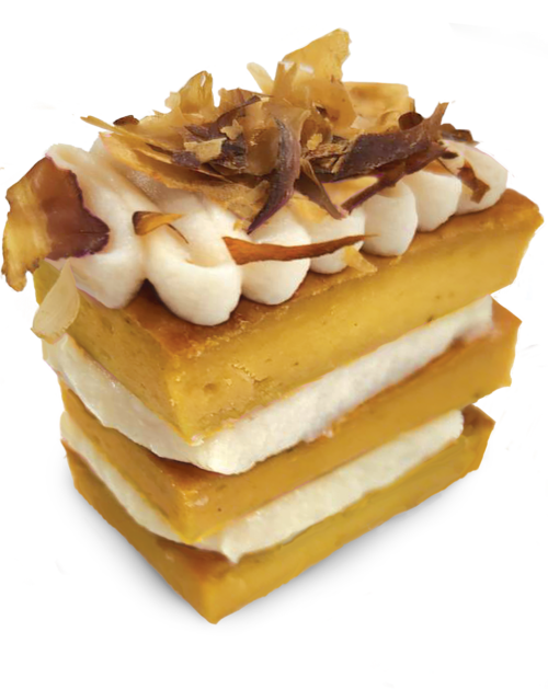 A three-layer "Happy Cakes for Dogs" dessert featuring yellow cake, a white cream filling, piped cream on top, and toasted coconut flakes as garnish, set against a plain background.