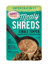 A pouch of Shreds Slow Cooked Shredded Chicken & Beef Kibble Topper is shown with a spoon over dry dog food.